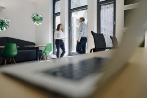 Foto van een laptop met op de achtergrond twee personen